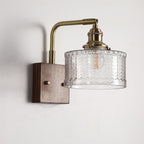 Clérachic fish-scale glass wall sconce in clear glass, the chevron columns lit from within against a plain white wall.