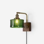 Studio shot of the Clérachic fish-scale glass wall sconce on white, green drum facing left above its slim plug-in cord.
