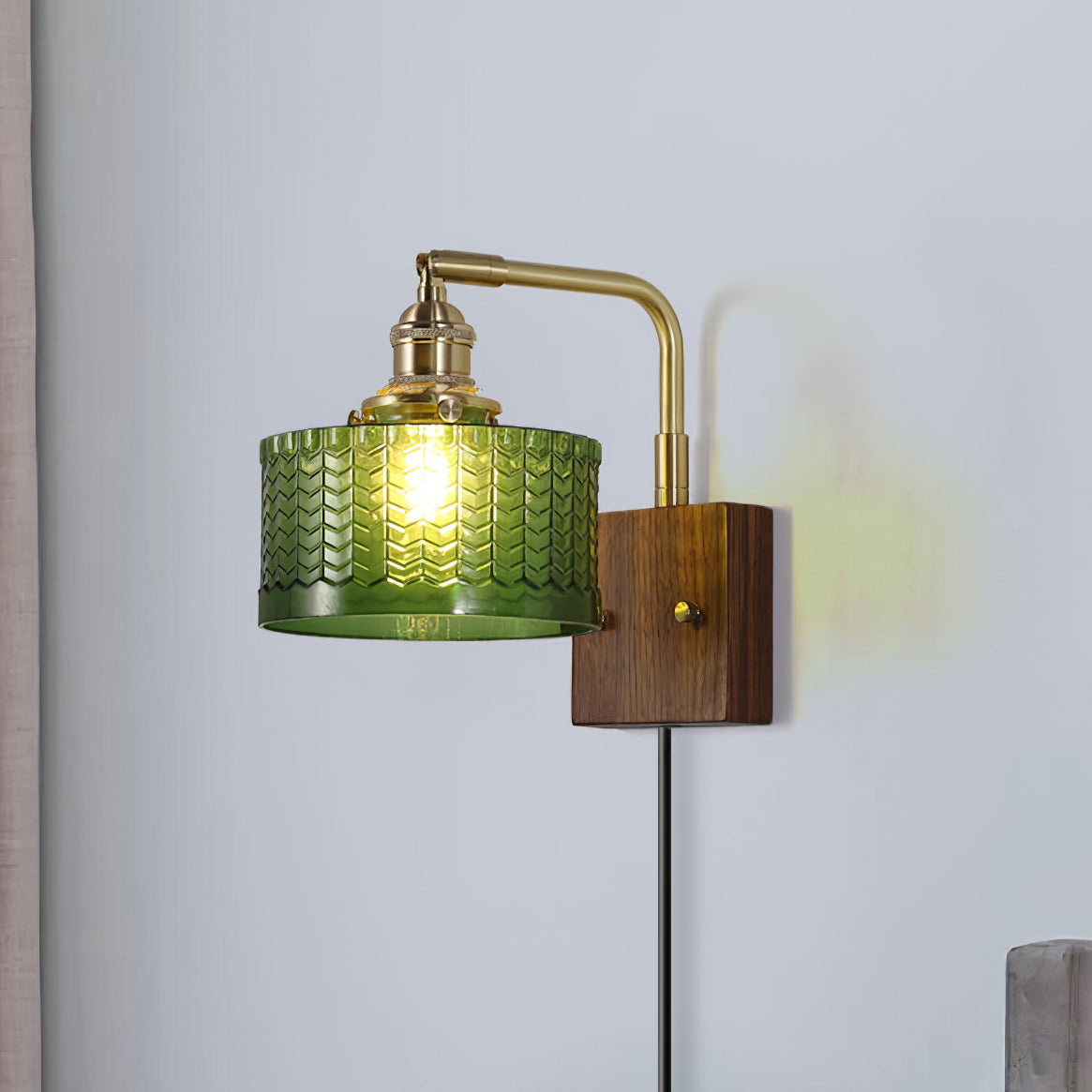 Clérachic fish-scale glass wall sconce lighting a bedroom corner, the green drum throwing a soft olive wash across the wall.