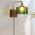 A Clérachic fish-scale glass wall sconce beside a house plant, sunlight and lamplight both catching the pressed green glass.