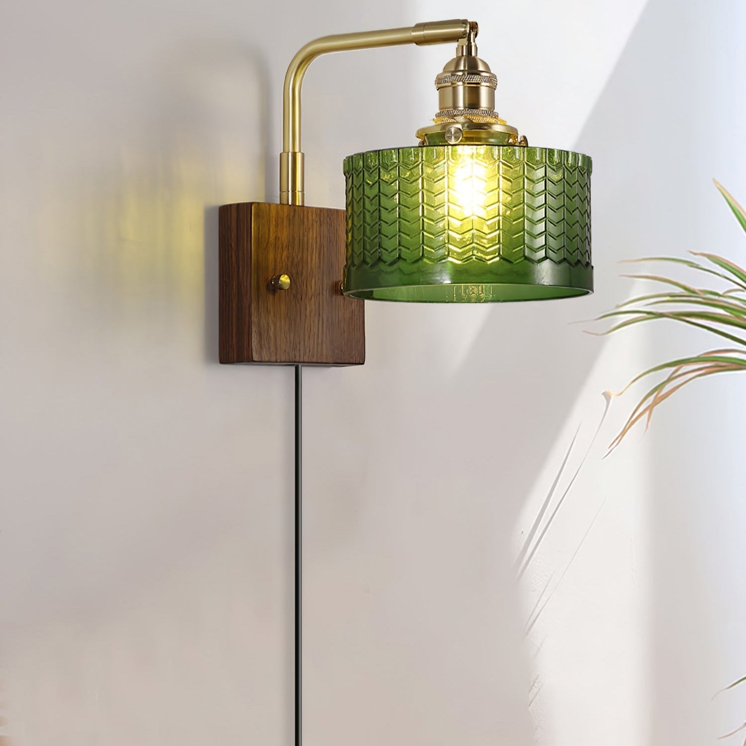 A Clérachic fish-scale glass wall sconce beside a house plant, sunlight and lamplight both catching the pressed green glass.