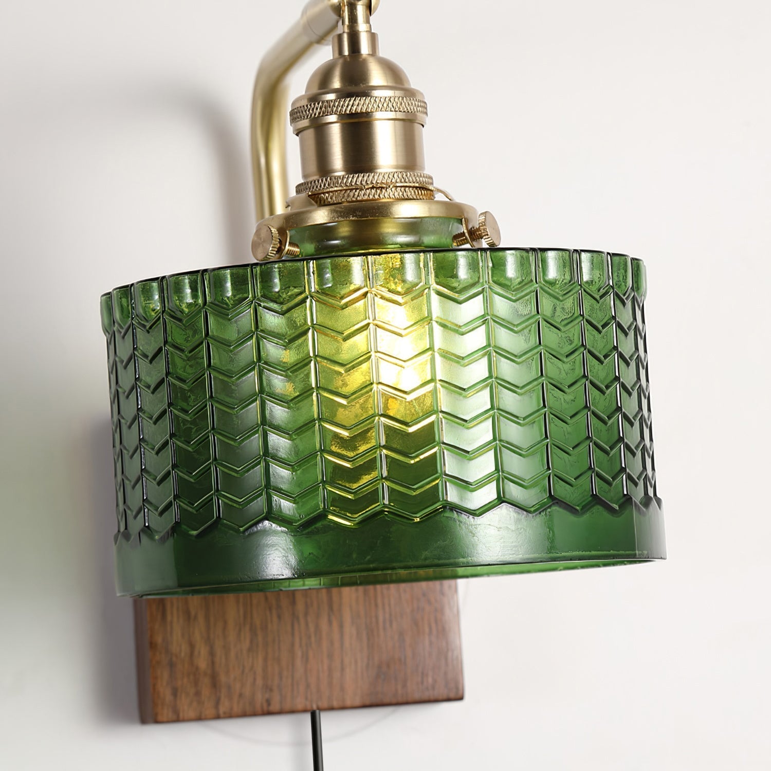 Close-up of the Clérachic fish-scale glass wall sconce shade, chevron relief and scalloped saw-tooth border under a brass holder.