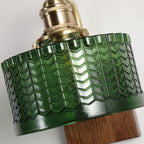 Macro detail of the Clérachic fish-scale glass wall sconce, deep bottle-green glass pressed into rows of stacked chevrons.