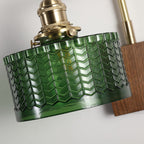 Detail of the Clérachic fish-scale glass wall sconce showing the brass thumbscrews that clamp the green glass drum in place.