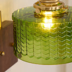 Close view over the Clérachic fish-scale glass wall sconce, the smooth glass top and brass collar above the chevron columns.