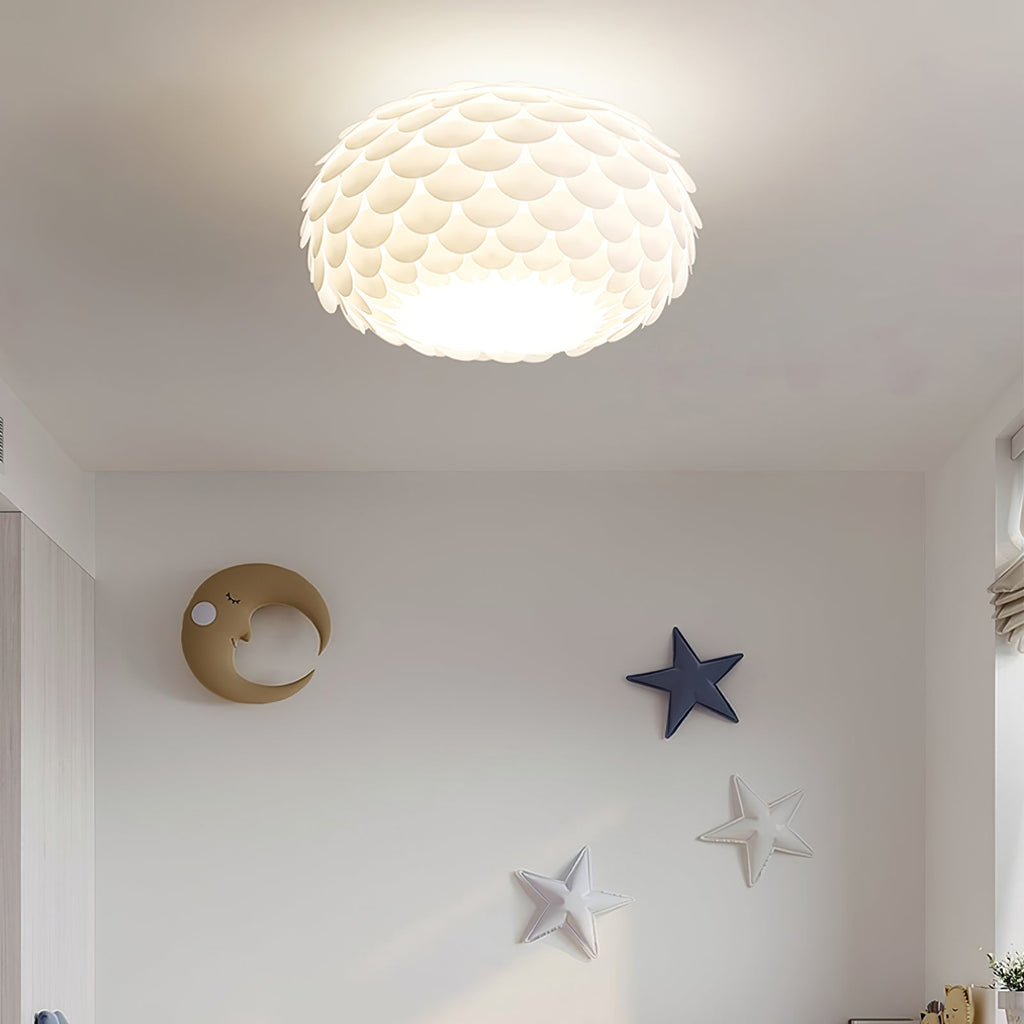 Lit Clérachic oval ceiling light with layered white scales above a pale wall decorated with a crescent moon and stars.