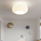 Lit Clérachic oval ceiling light with layered white scales above a pale wall decorated with a crescent moon and stars.