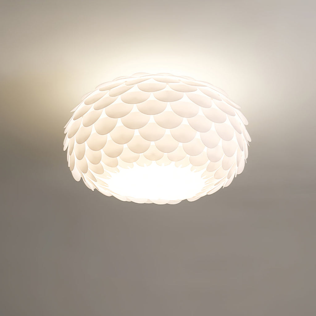 Close, low-angle view of the overlapping white scales and bright underside of this lit Clérachic ceiling light.