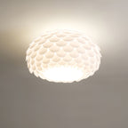 Close, low-angle view of the overlapping white scales and bright underside of this lit Clérachic ceiling light.