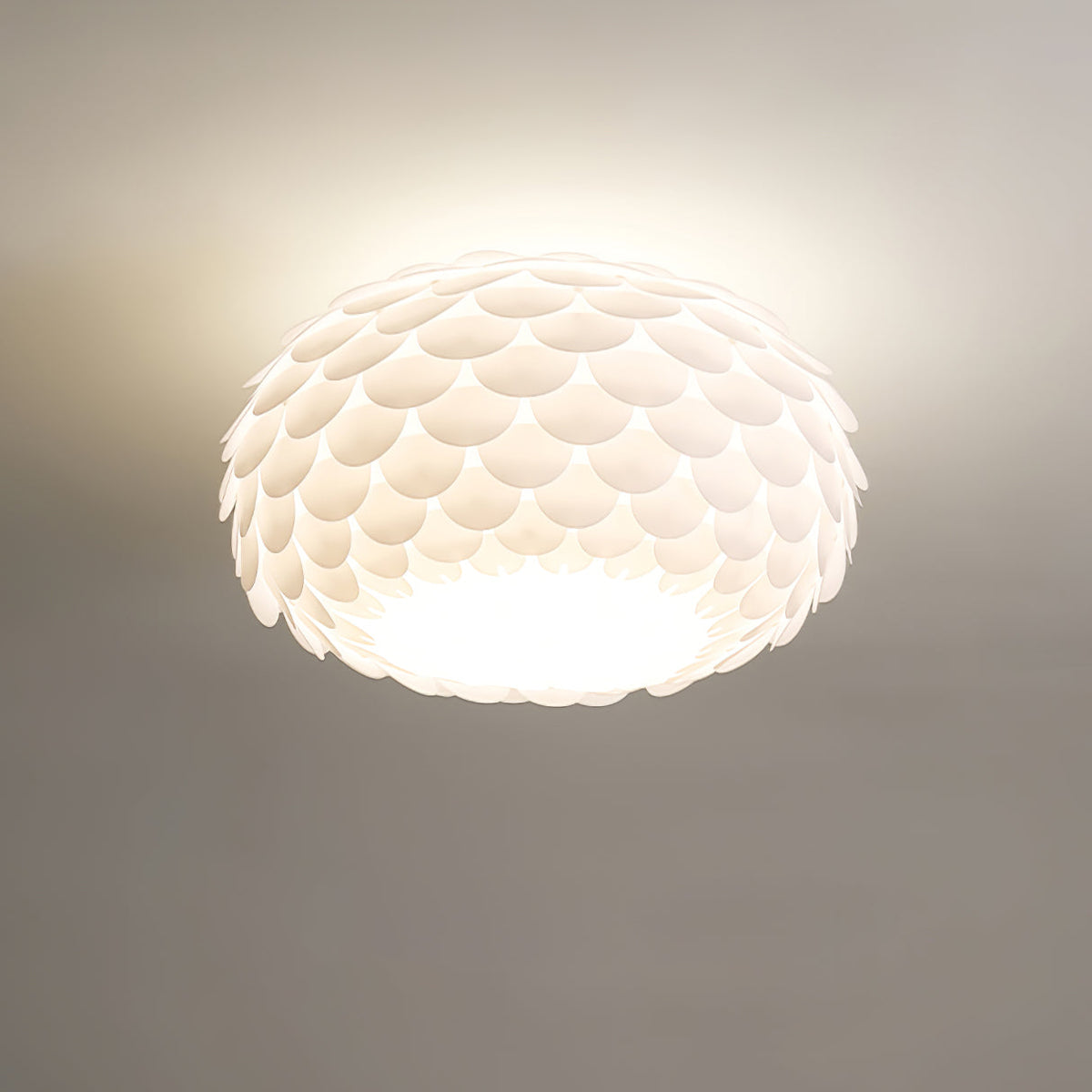 Close, low-angle view of the overlapping white scales and bright underside of this lit Clérachic ceiling light.