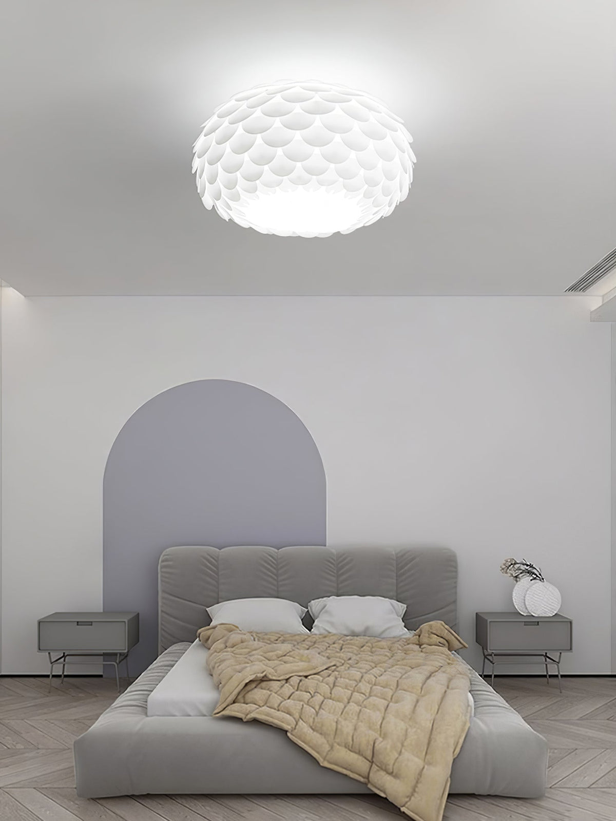 Clérachic oval ceiling light above a low grey upholstered bed with a pale arched panel on the wall behind.