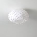 Unlit Clérachic ceiling light with layered white scales, seen from below against a pale grey ceiling.