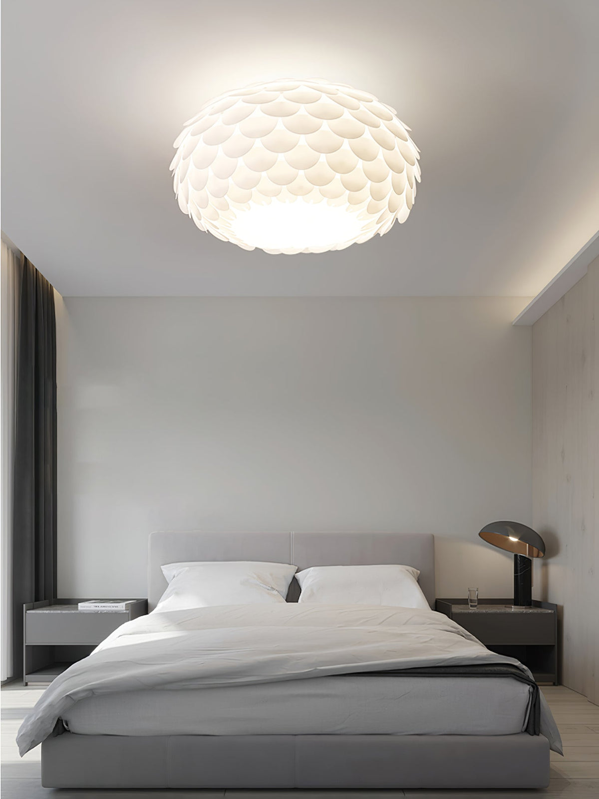 Clérachic fish-scale ceiling light above a grey bed with dark bedside tables, a table lamp and dark curtains.