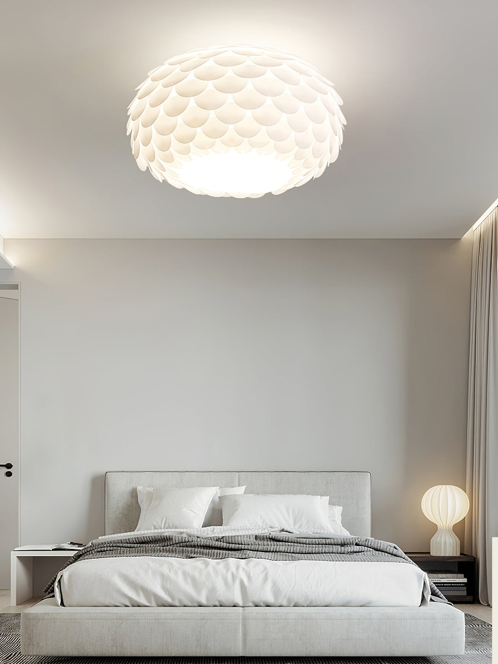 A Clérachic ceiling light in a calm grey bedroom, with a grey upholstered bed and a small round table lamp.