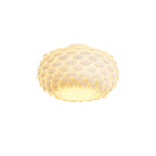 Clérachic oval ceiling light in warm white light, its scales glowing softly, on a white background.