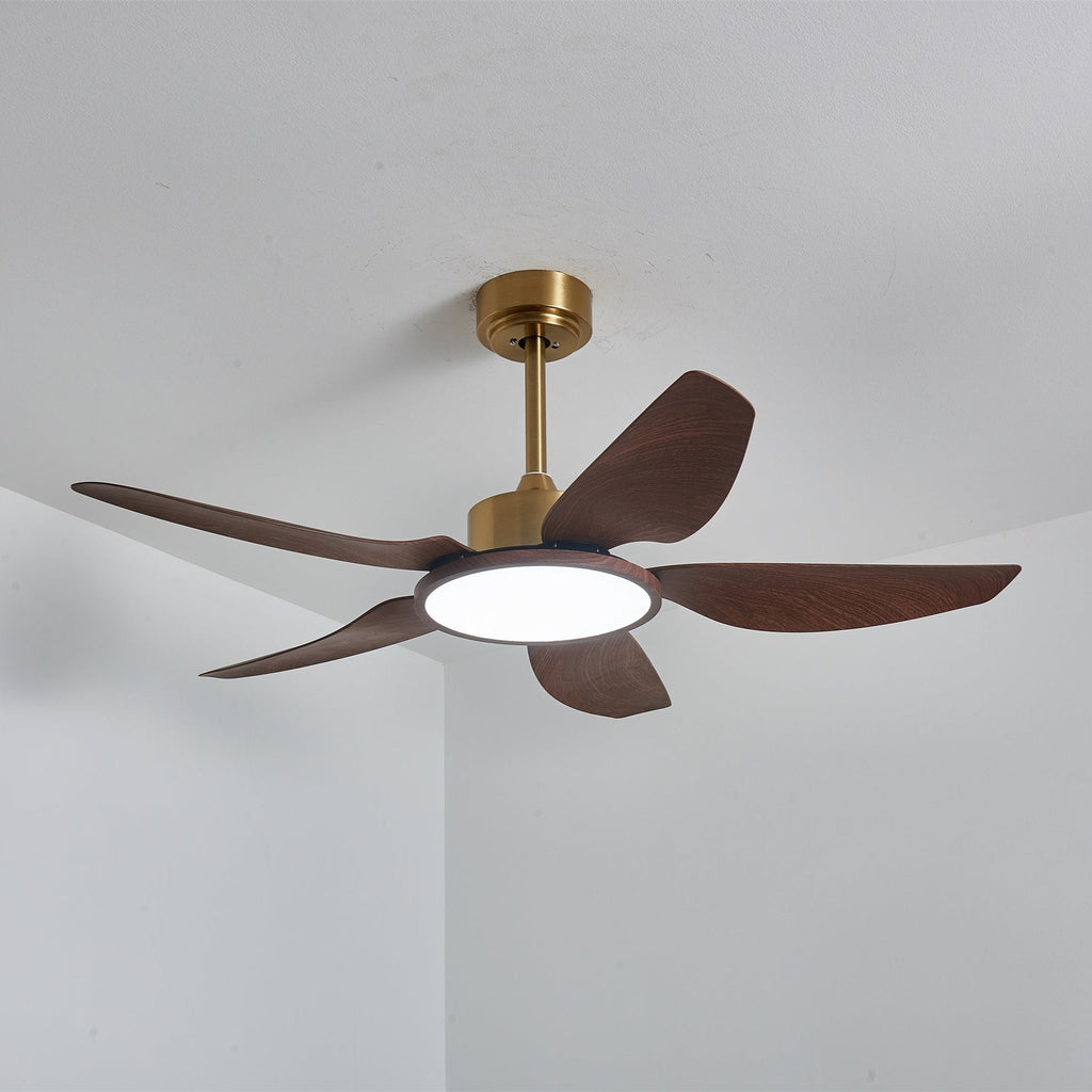 A Clérachic walnut-grain ceiling fan seen from below against a white ceiling, its round light on in a cool white.