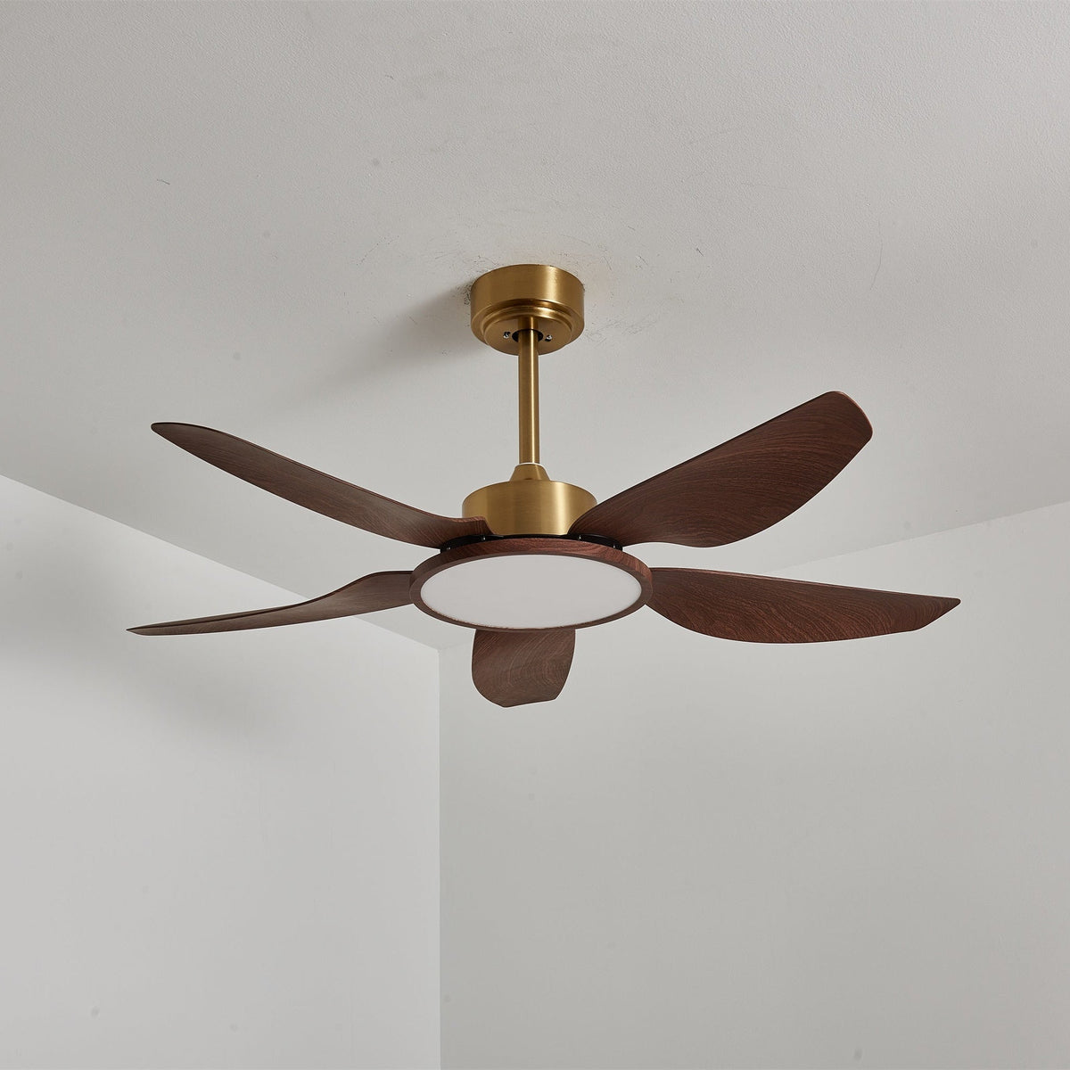 The Clérachic ceiling fan from the side with its light off, showing a gold down-rod and five walnut-grain blades against a white ceiling.