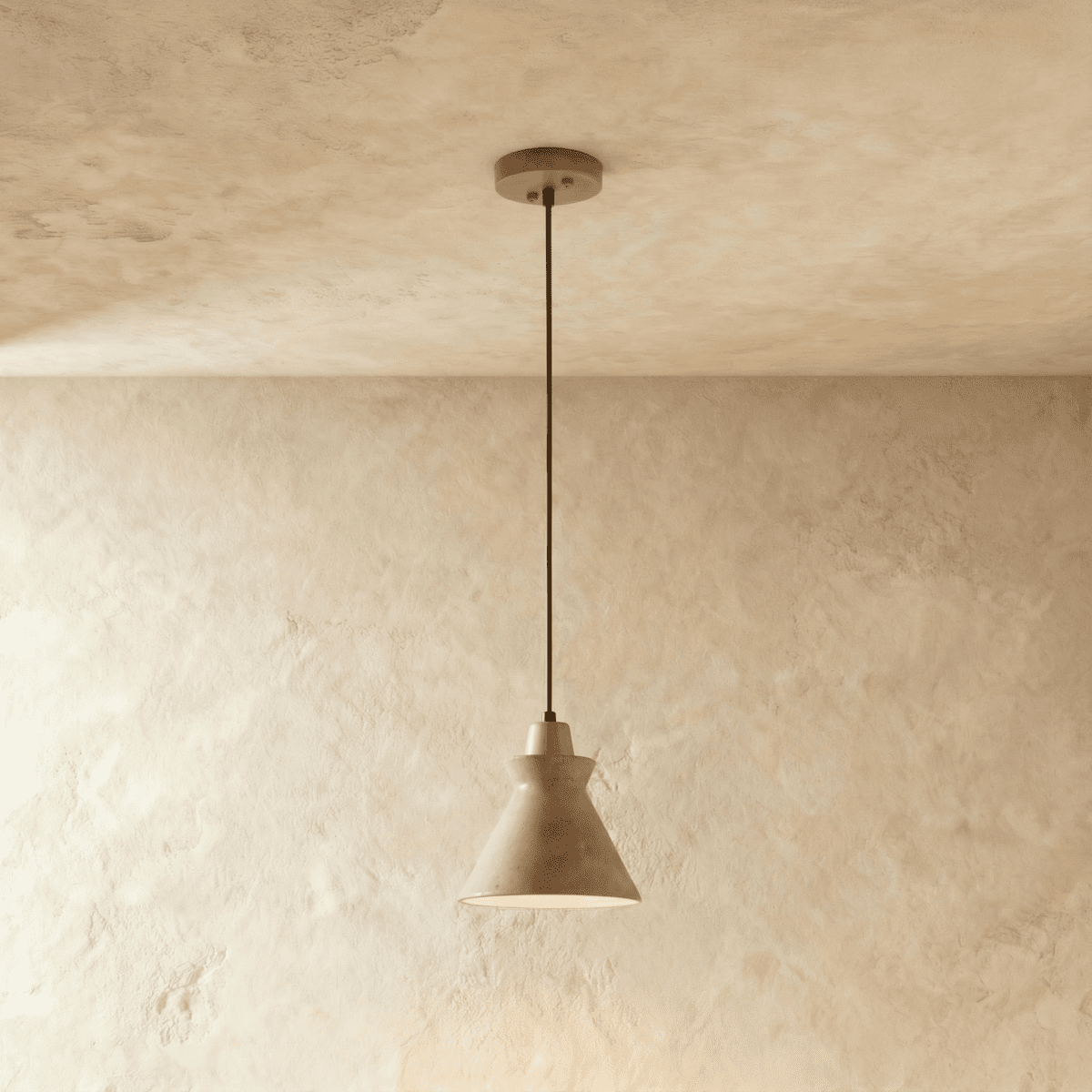 Clérachic flared travertine pendant with a small wooden collar, hung on a slim cord against a limewashed plaster wall