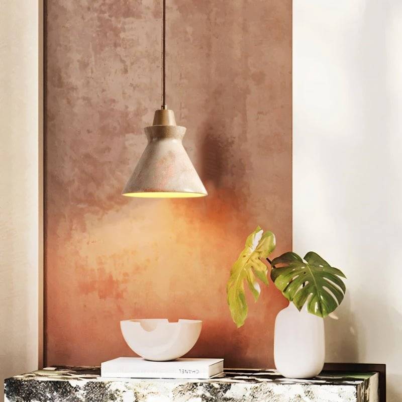 Clérachic travertine pendant glowing warm over a marble console, with a monstera leaf in a white vase and a bowl