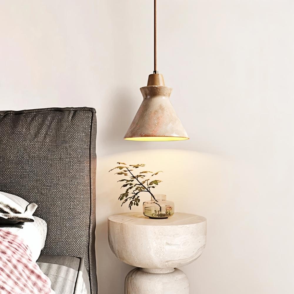 Clérachic travertine pendant with a wooden accent hanging beside a bed, lighting a round stone bedside table