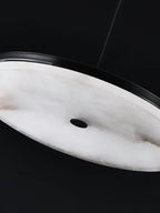 Close-up of the Clérachic Flat Disc Pendant Light from below, showing the veined alabaster underside and its small central vent.