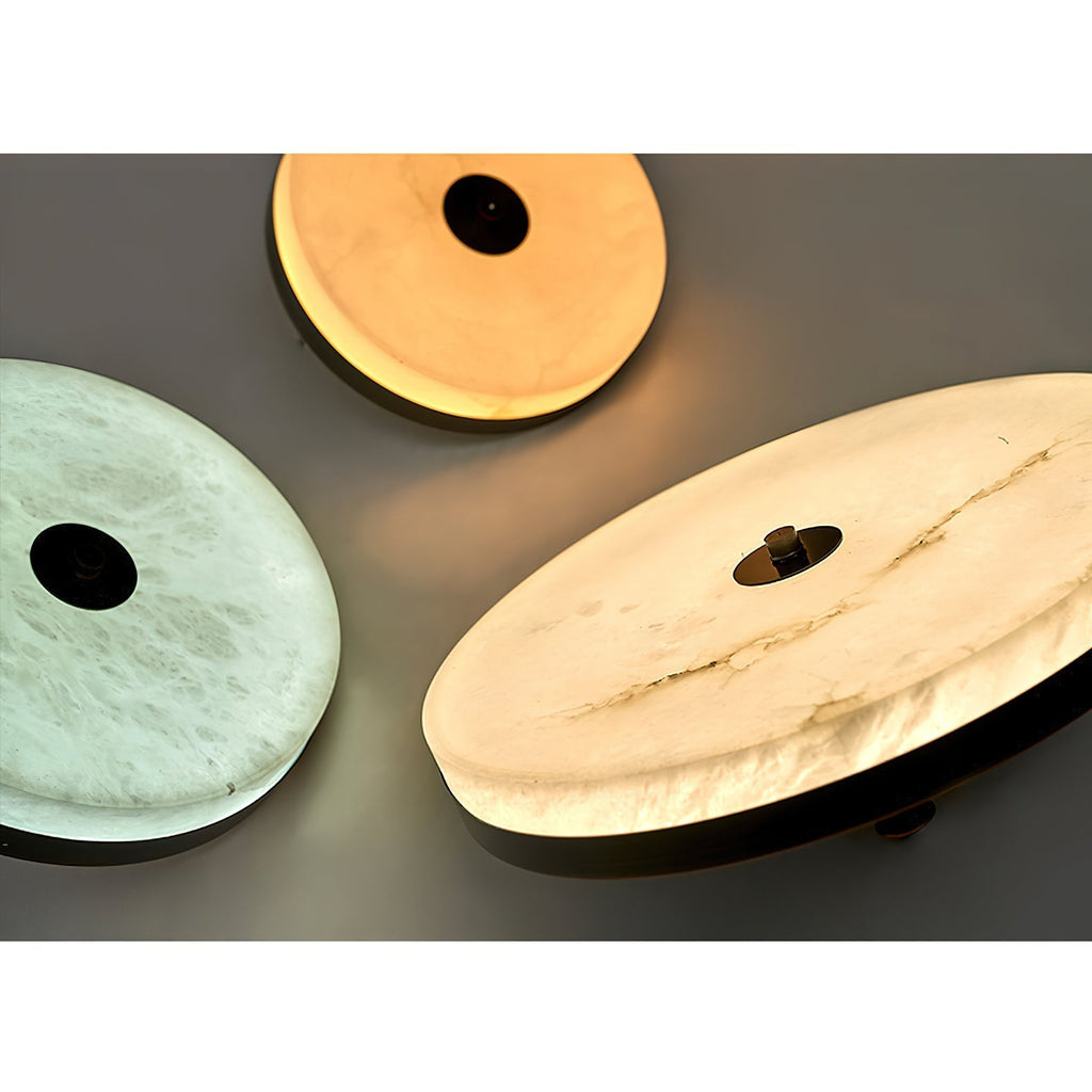 Three Clérachic Flat Disc Pendant Light shades side by side, comparing cool white and warm honey light through the alabaster.