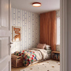 Clérachic red flush ceiling light above a child's bedroom with aeroplane wallpaper, a patchwork quilt and rust curtains.