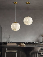 Two Clérachic alabaster pendants hung at staggered drops above a dark kitchen island.