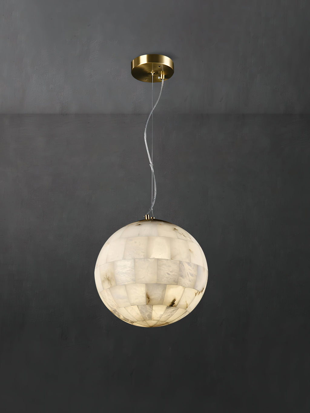 The Clérachic pendant against grey plaster, full drop shown from brass canopy through the looped cable.