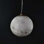 Clérachic alabaster globe on black, the hand-tiled stone panels meeting a slim brass collar at the top.