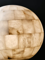 Clérachic alabaster globe backlit, the stone reading honey-warm where light passes through the tiles.