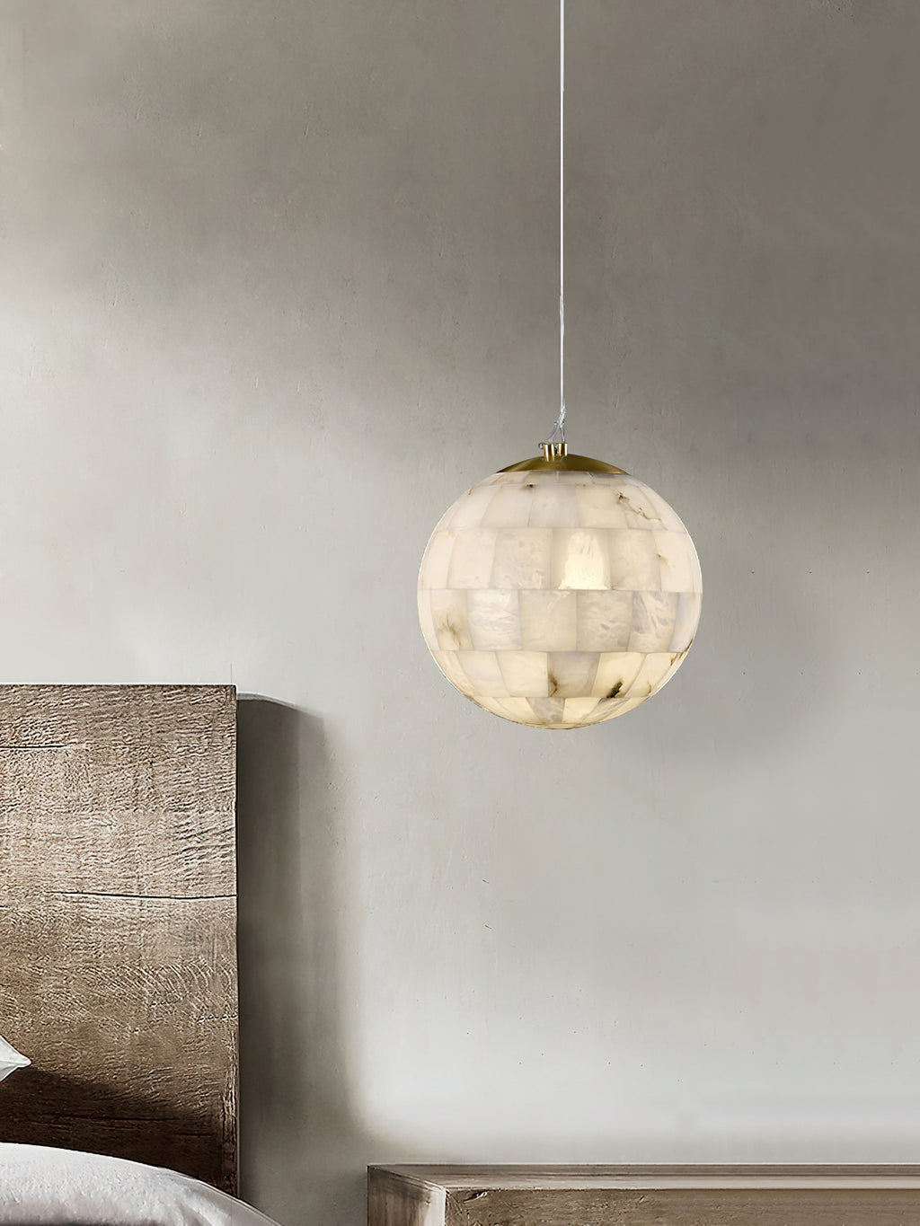 Clérachic alabaster pendant hanging over a bench beside a timber headboard in a soft plaster bedroom.