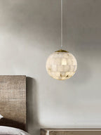 Clérachic alabaster pendant hanging over a bench beside a timber headboard in a soft plaster bedroom.