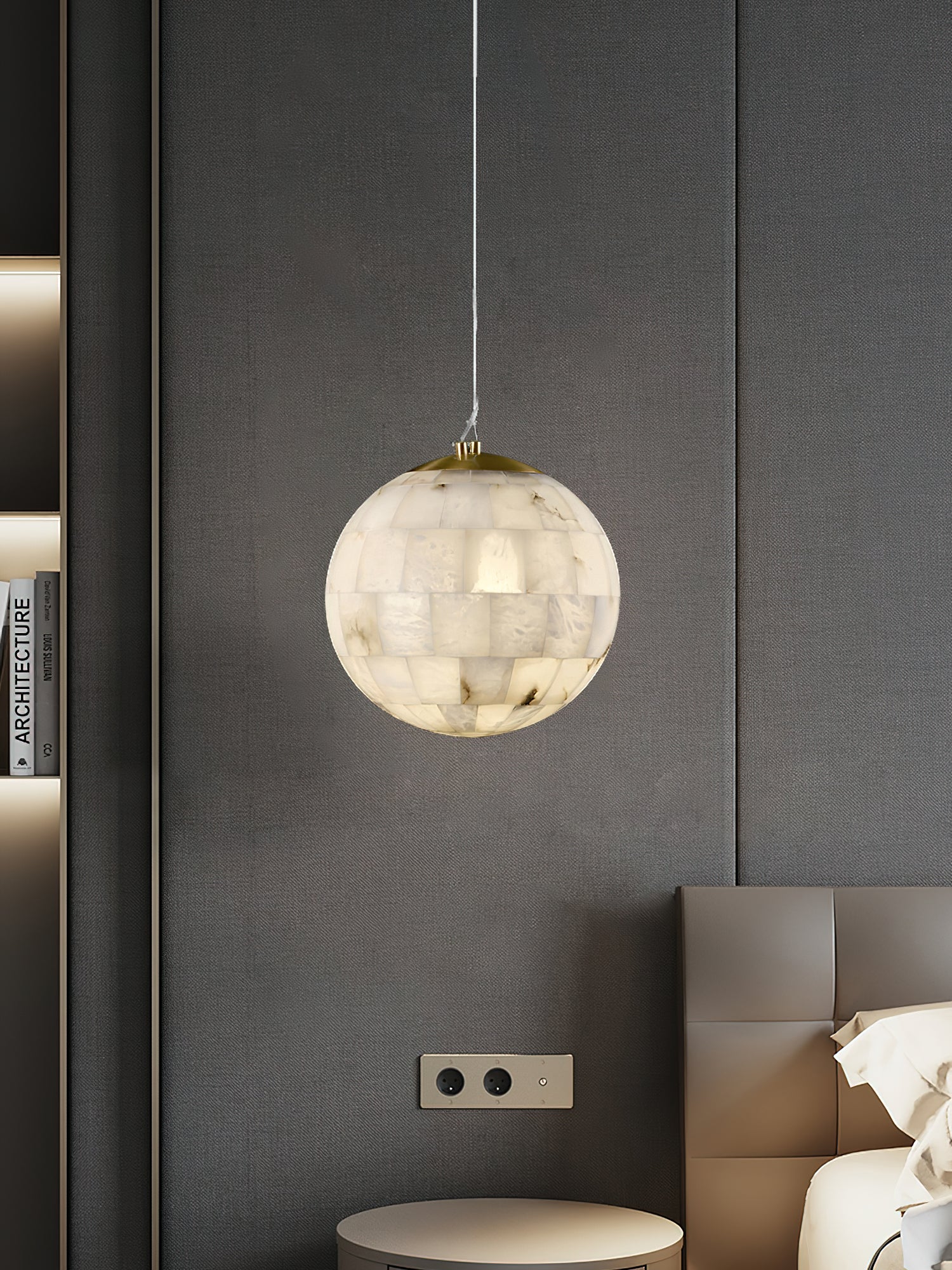 The Clérachic globe pendant lit against dark grey wall panels, beside a low bedside table and shelving.