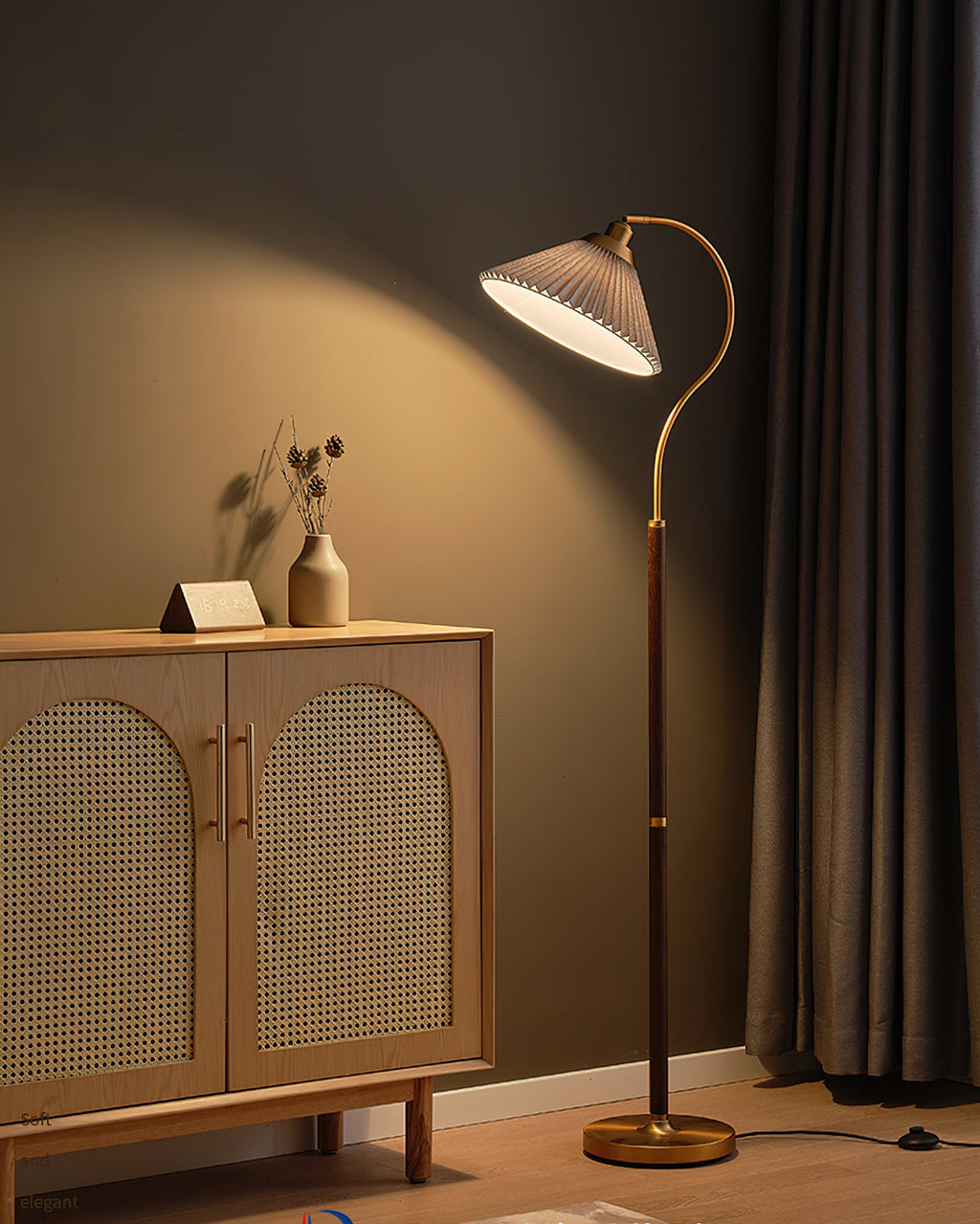 A Clérachic floor lamp with a white pleated shade, a walnut stem and a brass base, beside an oak cabinet with cane doors.