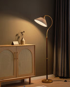 A Clérachic floor lamp with a white pleated shade, a walnut stem and a brass base, beside an oak cabinet with cane doors.