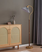 A Clérachic floor lamp with a grey pleated shade by the same cane cabinet and grey curtains, shown unlit.
