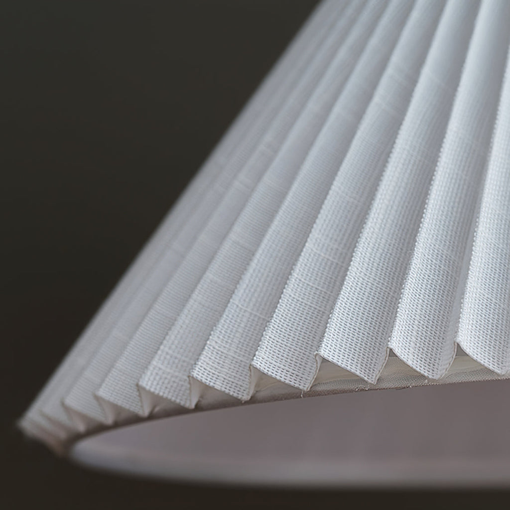 Close view of the fine pleats and woven fabric on the underside of the white shade of this Clérachic floor lamp.