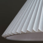 Close view of the fine pleats and woven fabric on the underside of the white shade of this Clérachic floor lamp.