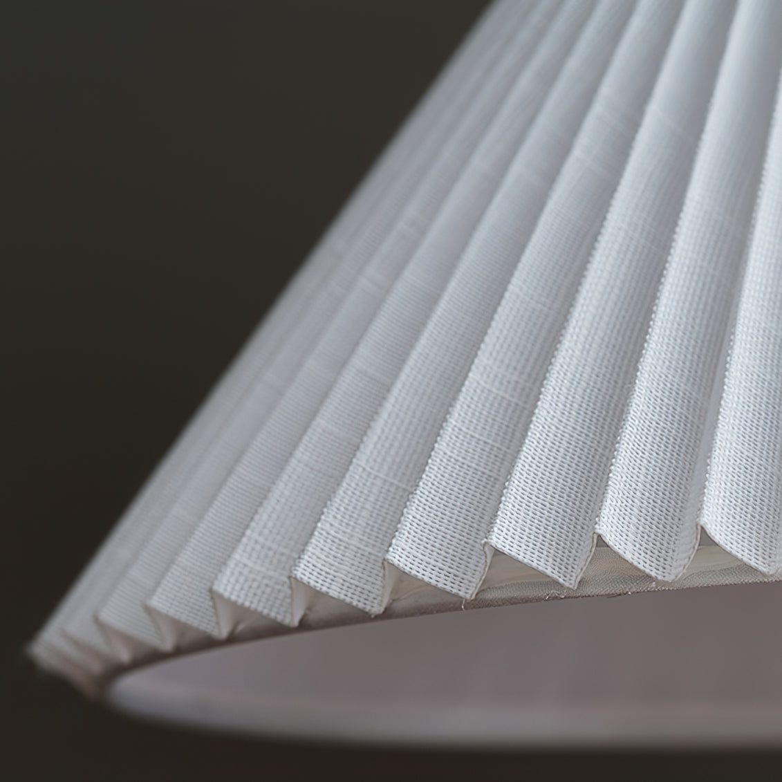 Close view of the fine pleats and woven fabric on the underside of the white shade of this Clérachic floor lamp.