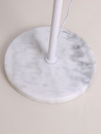 Close view of the round white marble base and the cord leaving the pole of this Clérachic floor lamp.