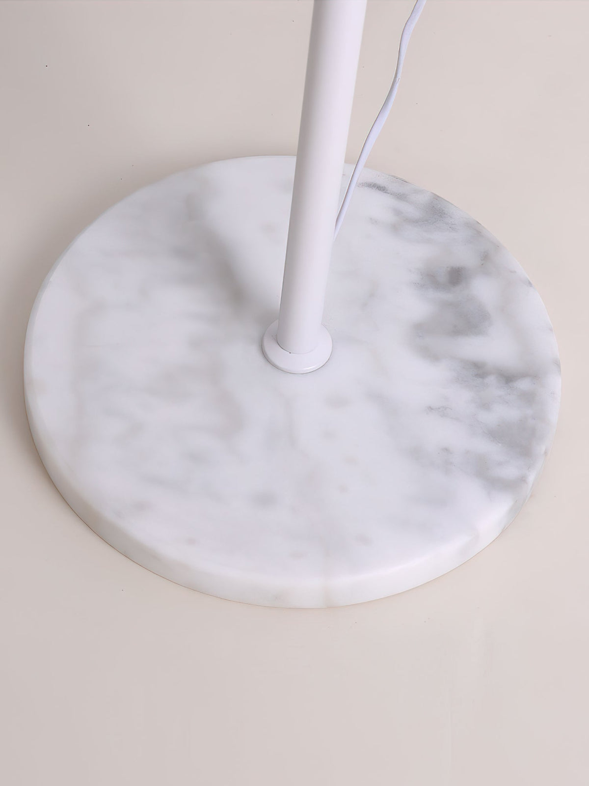 Close view of the round white marble base and the cord leaving the pole of this Clérachic floor lamp.