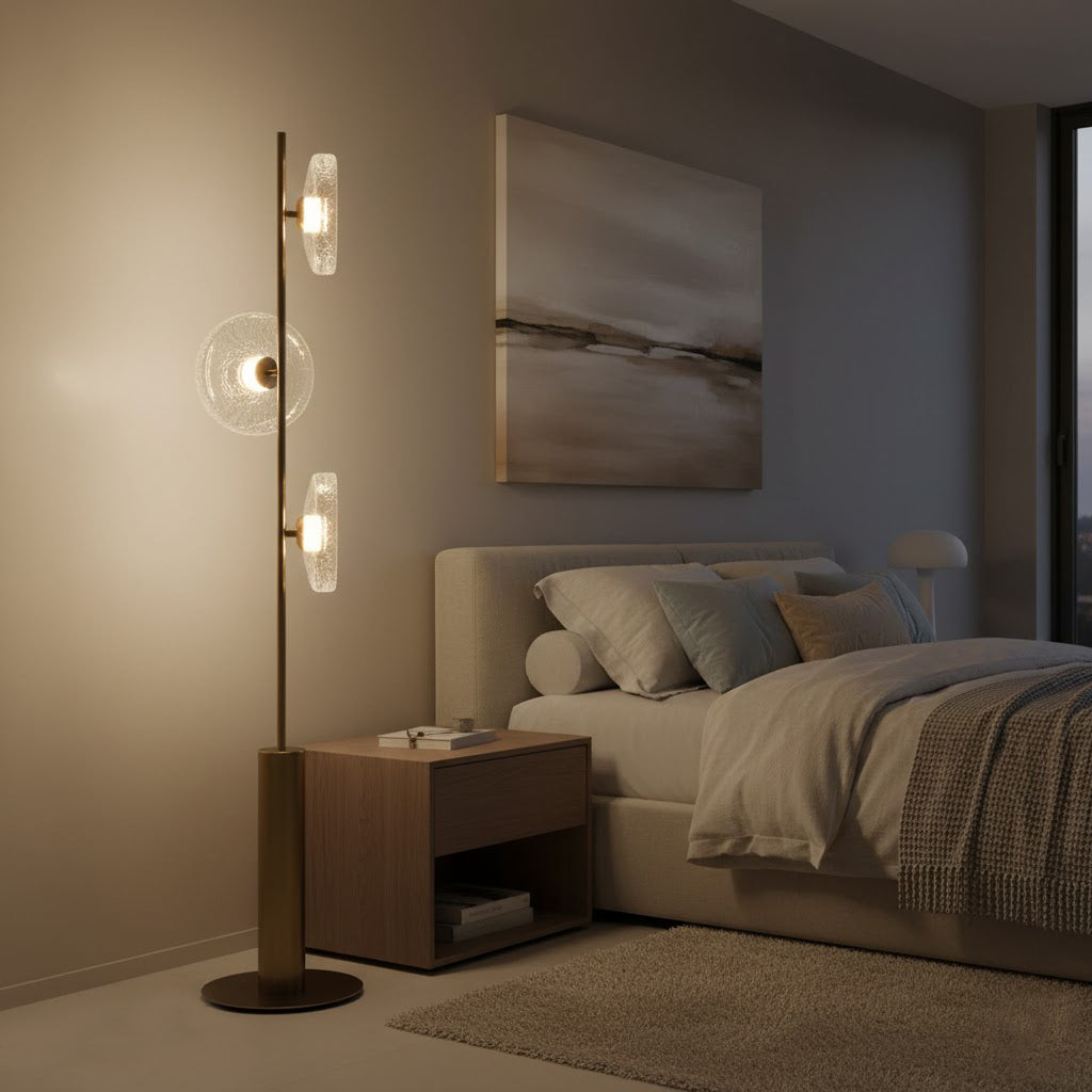 This Clérachic floor lamp stands in a bedroom beside a wooden bedside table, with an abstract landscape print on the wall.
