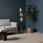 This Clérachic floor lamp stands in the corner of a navy room beside a potted fiddle-leaf fig and a grey sofa.