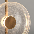 Close view of the cracked glass disc, brass-toned centre cap and stem on this Clérachic floor lamp, with light glowing behind it.