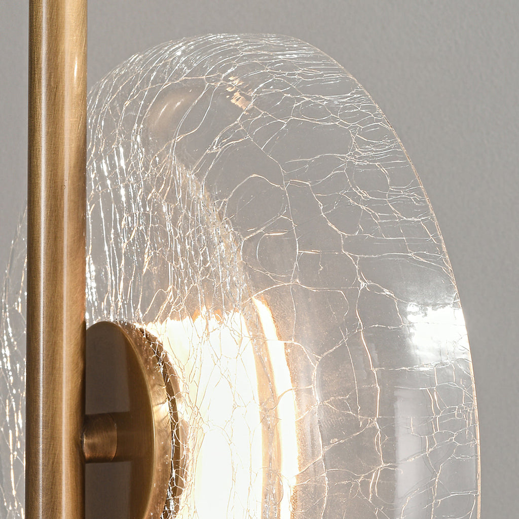 Close view of the veined, cracked glass disc and bronze stem on this Clérachic floor lamp, with a bright light behind the cap.