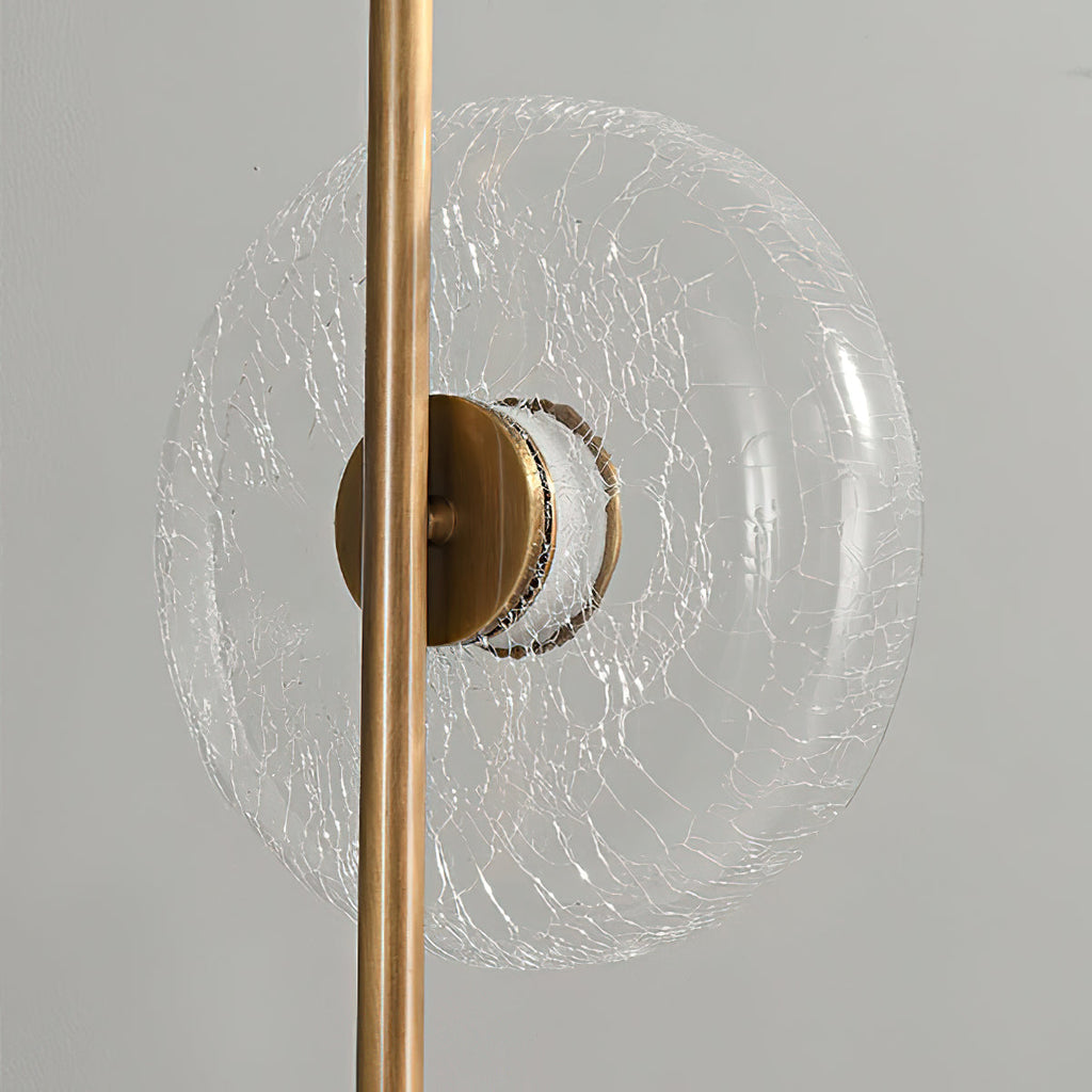 Close view of a clear glass disc with a fine crackle pattern, held by a bronze cap on this Clérachic floor lamp.