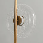 Close view of a clear glass disc with a fine crackle pattern, held by a bronze cap on this Clérachic floor lamp.