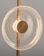 Close view of a lit cracked glass disc with a warm glow around its bronze centre cap, on this Clérachic floor lamp.