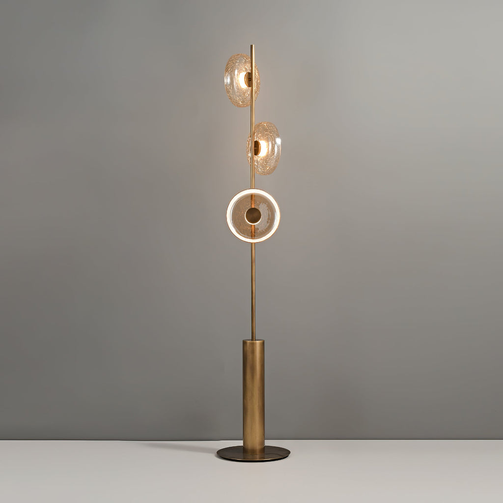 This Clérachic floor lamp switched on, with the lowest disc lit as a bright ring and the upper two glowing amber.